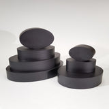 alt="seven black resin oval plinths stacked in two piles on a white background"