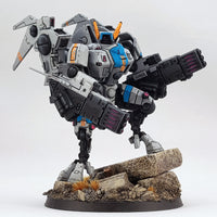 alt="painted tau coldstar fusion arms assembled on plastic battlesuit, pictured with foot up on concrete slab looking directly at camera"