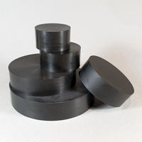 alt="five round black resin plinths in a loose stack against a white background"