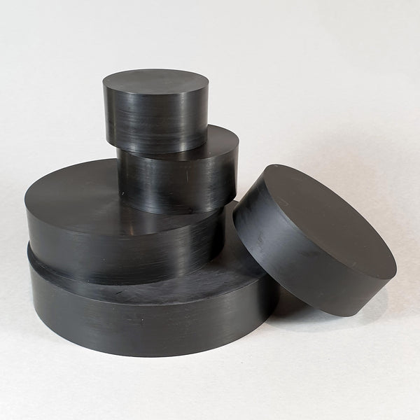 alt="five round black resin plinths in a loose stack against a white background"